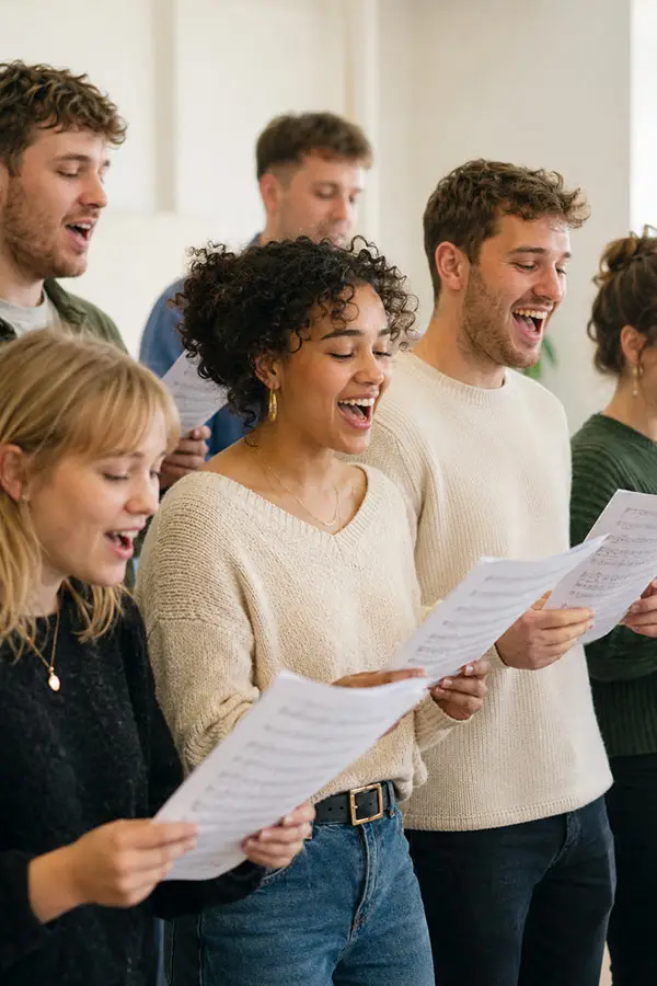 Adults singing together while holding sheet music