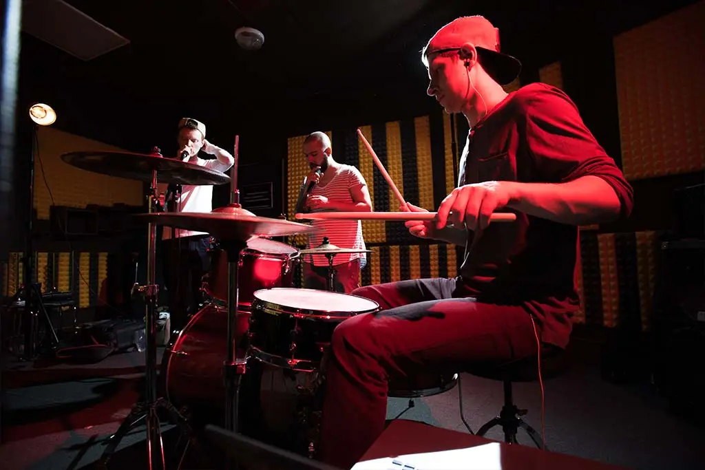 Image of band of young musicians performing in recording studio