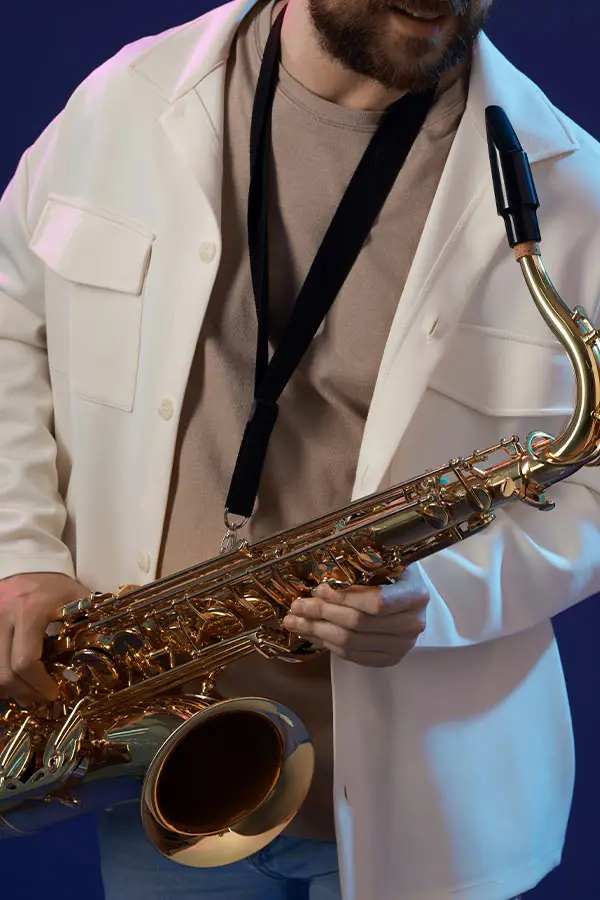 Bearded man in a white jacket holding a saxophone