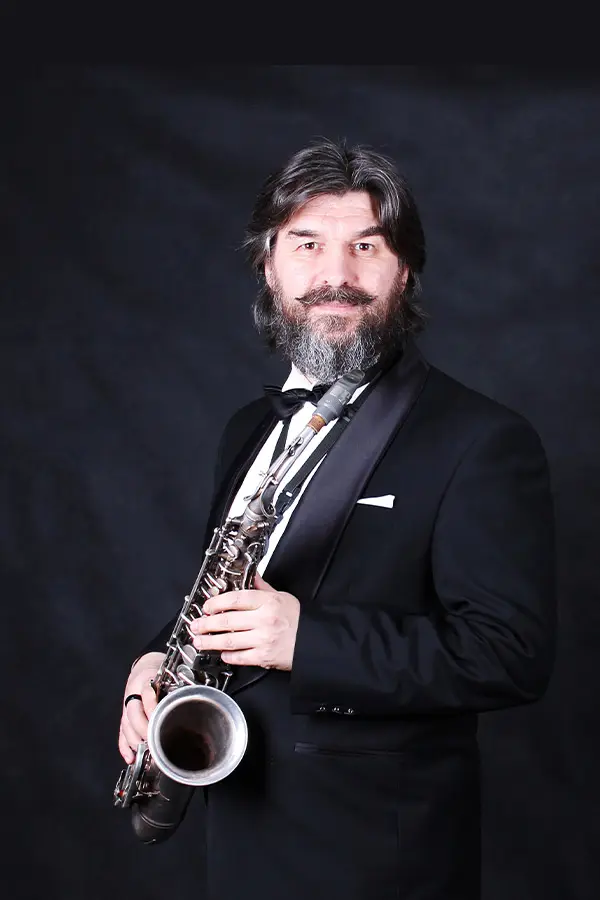 Bearded man in a tuxedo holding a saxophone