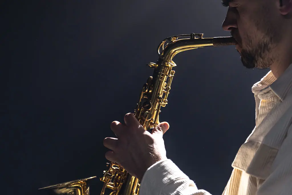 Bearded man playing saxophone in low light