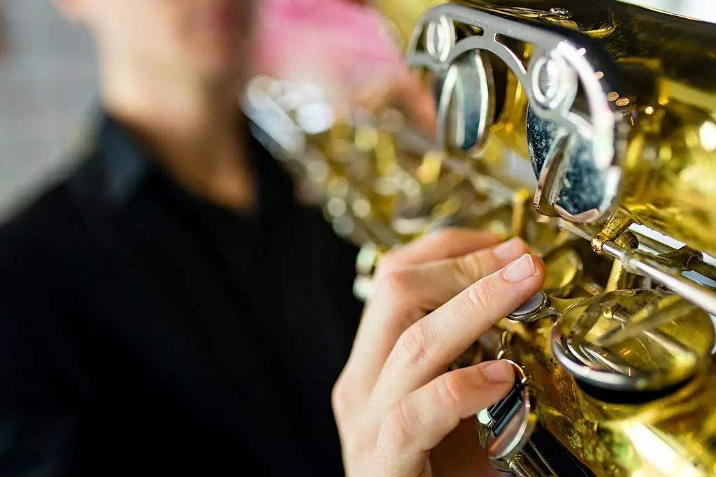 Fingers pressing saxophone keys beside a black shirt