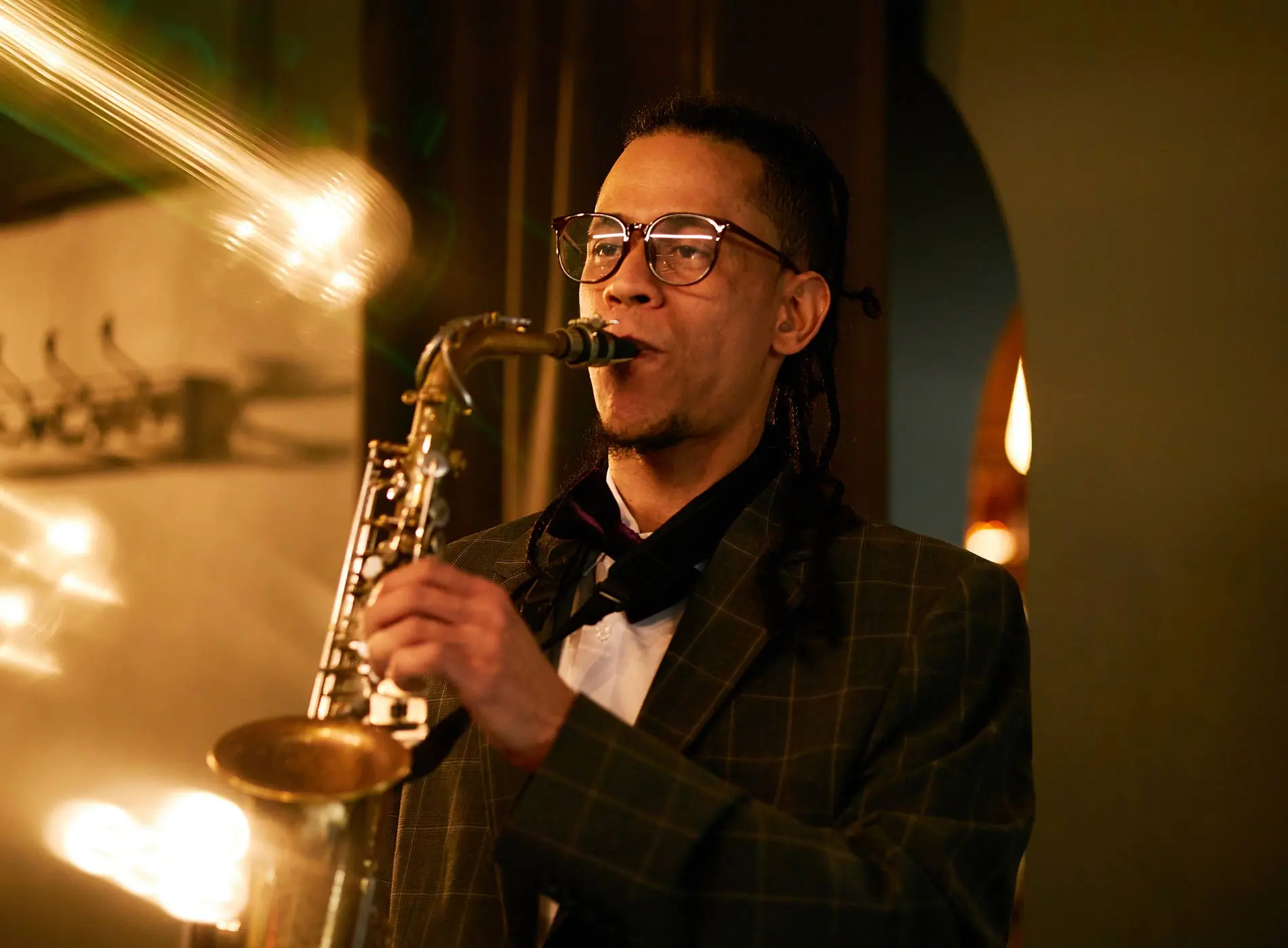 Man with glass and suit playing saxophone