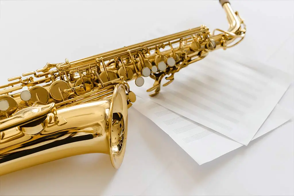 Gold saxophone resting on blank music paper