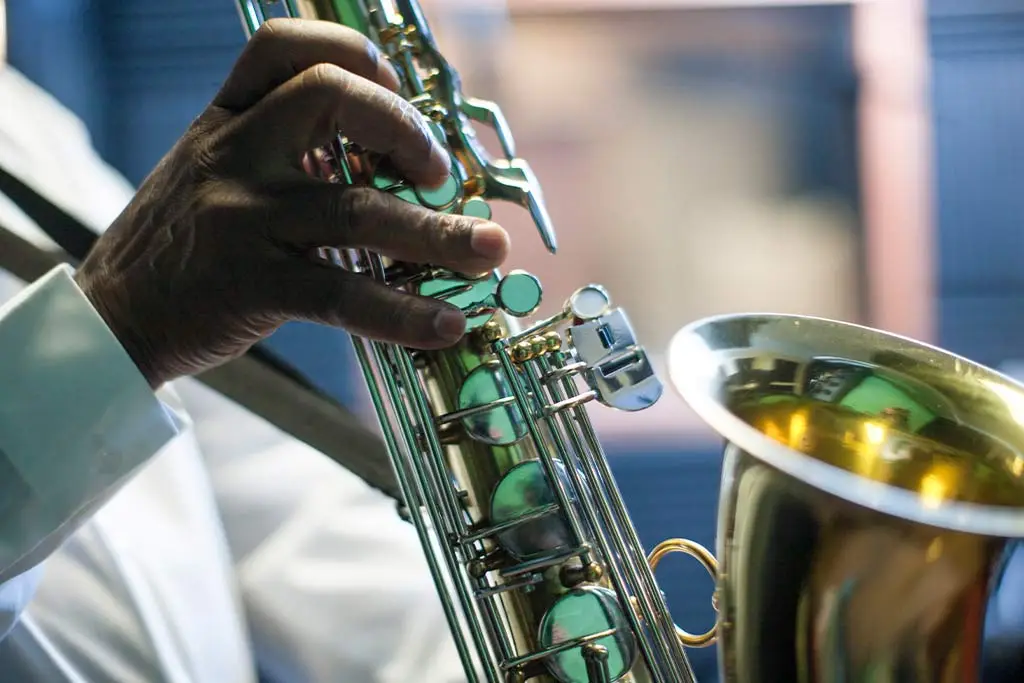Hand in a white sleeve pressing saxophone keys
