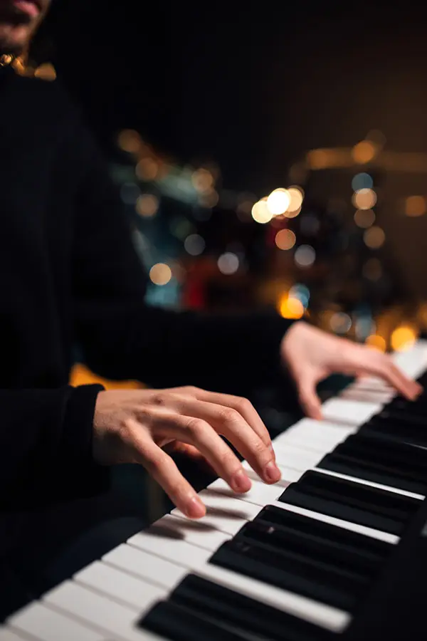 Hands playing a piano keyboard in low light