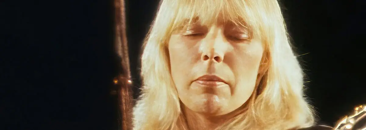 Joni Mitchell playing guitar and singing