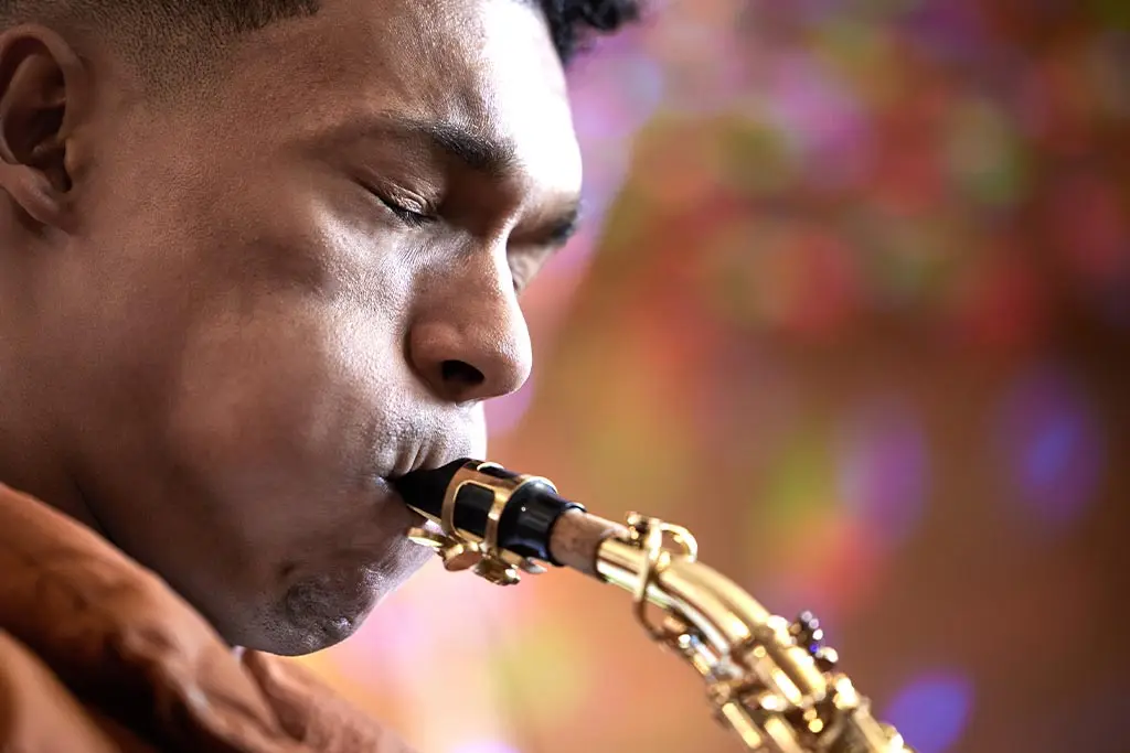 Man blowing into a saxophone mouthpiece in close-up