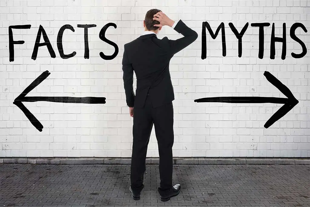 Man in suit facing facts and myths on a wall