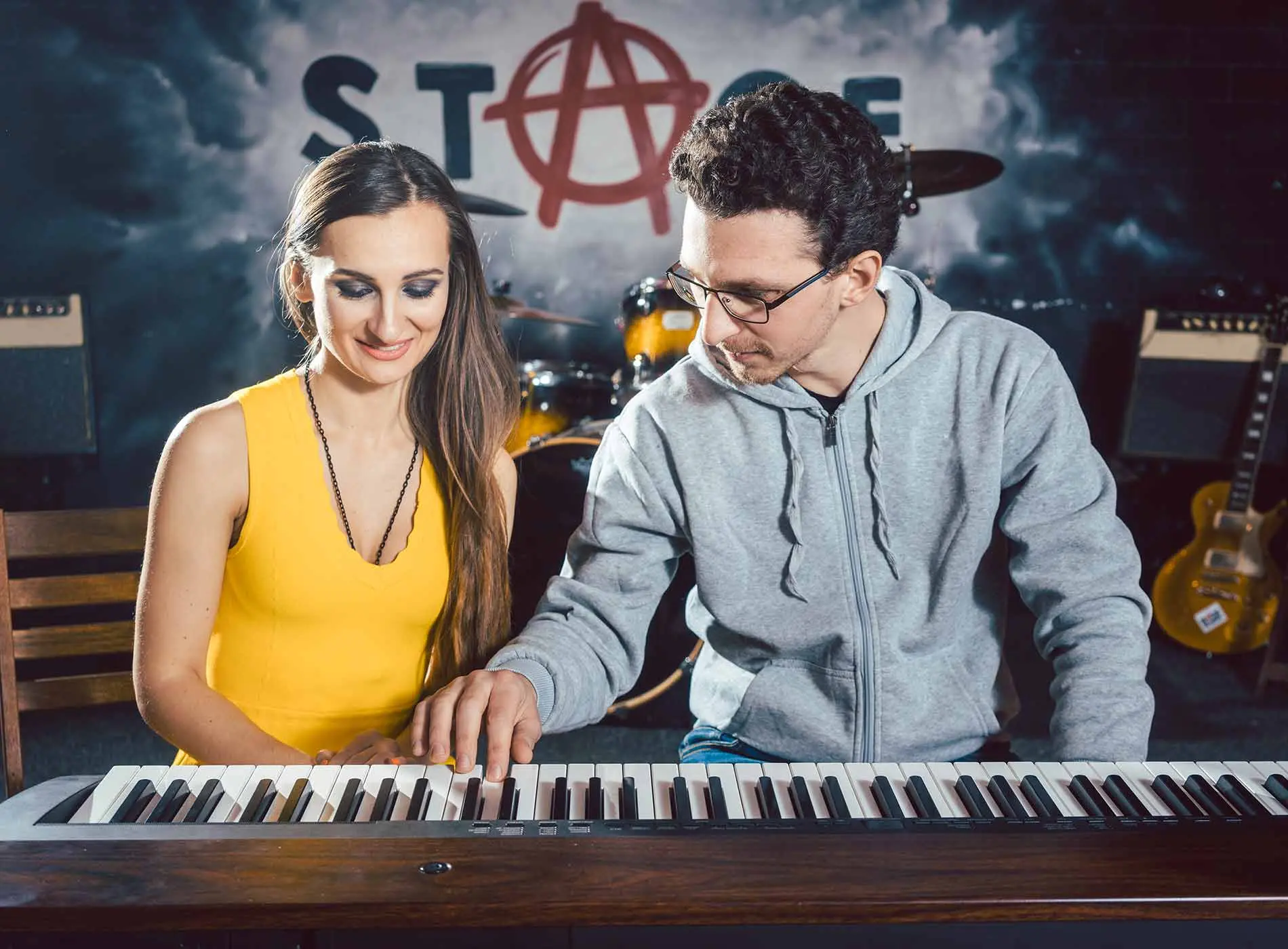 A male piano teacher giving lesson to his female student