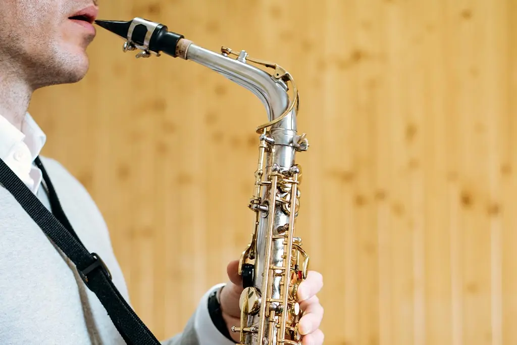 Man holding a saxophone mouthpiece at his lips