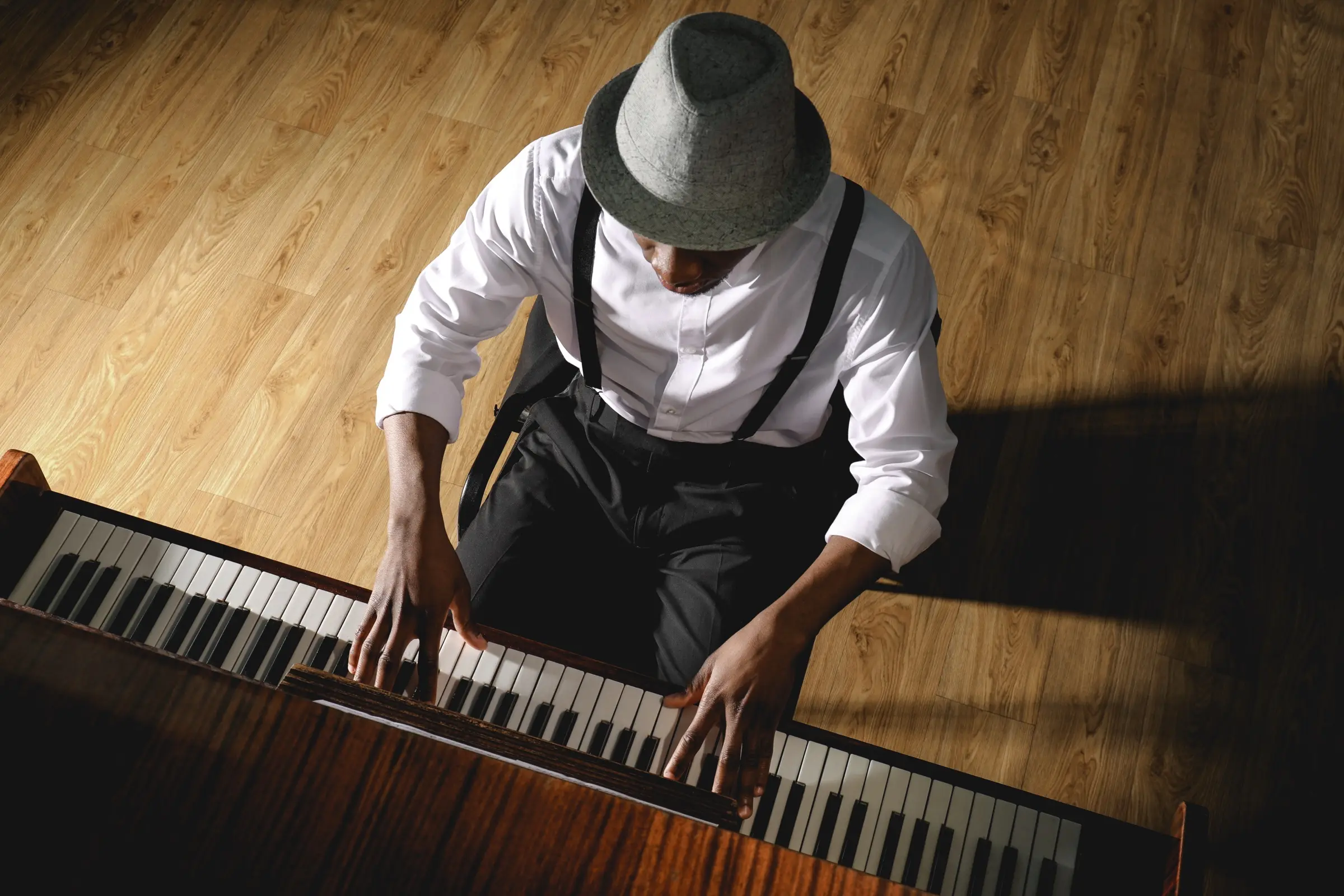 Overhead view of a man in a hat playing the piano.