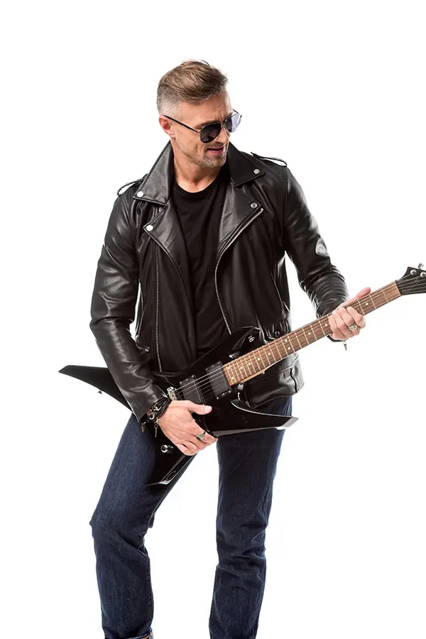 Man in a leather jacket playing an angular black electric guitar
