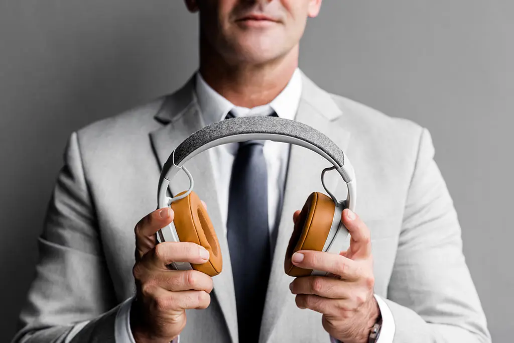 Suited man holding a pair of headphones