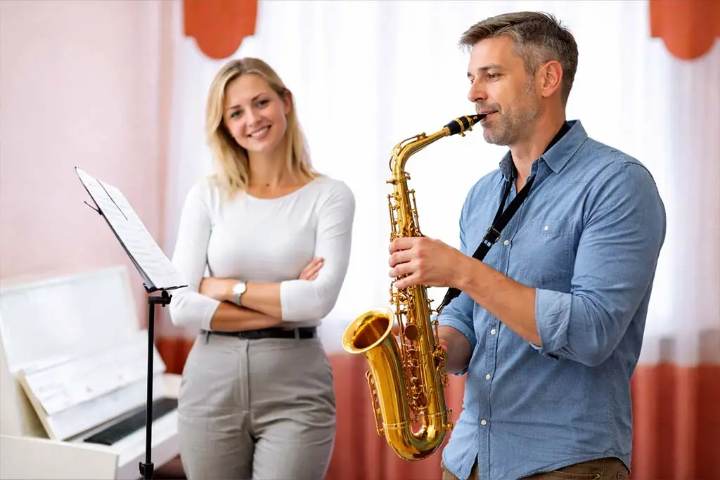 Man playing alto saxophone beside a woman and music stand