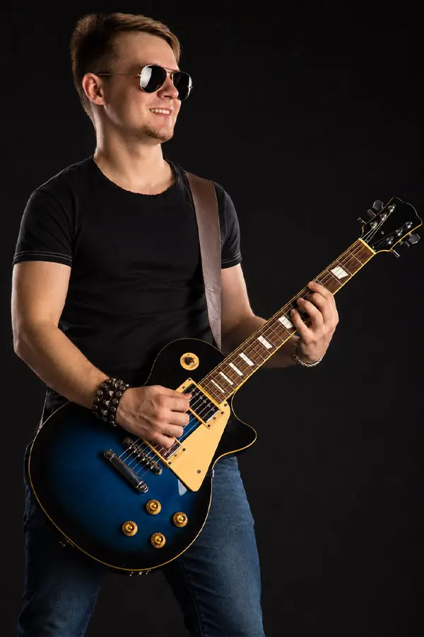 Man wearing sunglasses playing a blue electric guitar