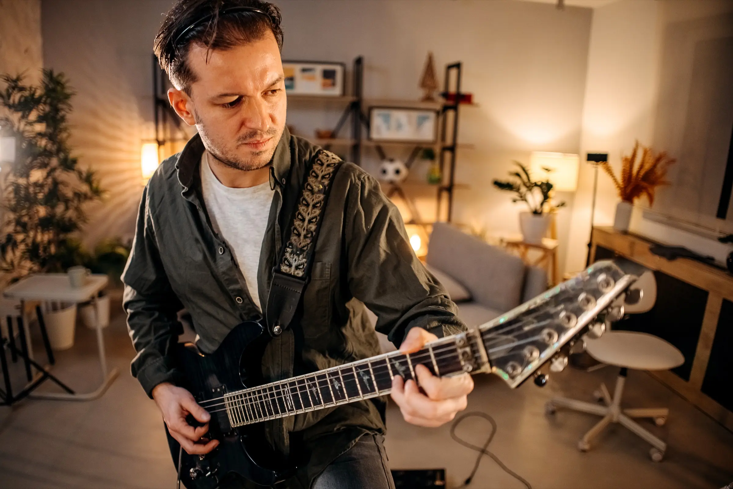 Man playing an electric guitar in a home studio.