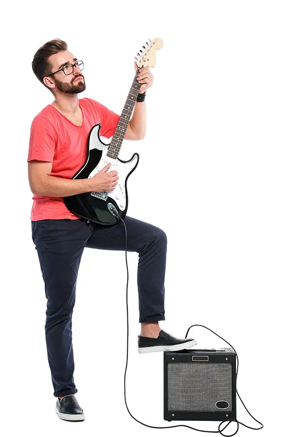 Man playing an electric guitar beside a small amplifier