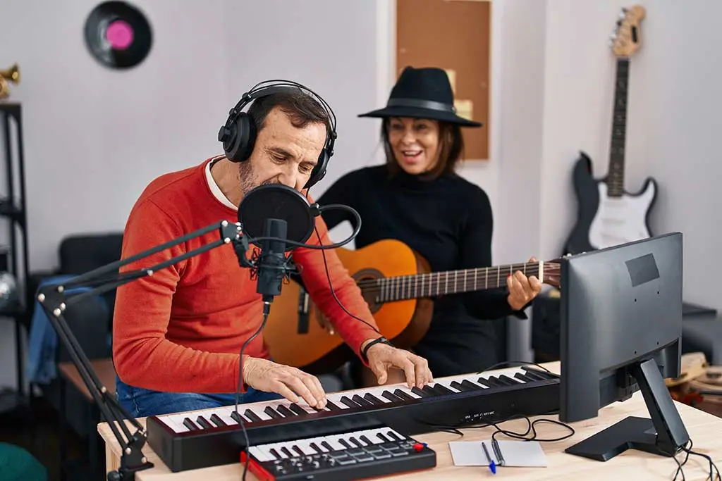 Man playing keyboard while woman plays acoustic guitar in a studio