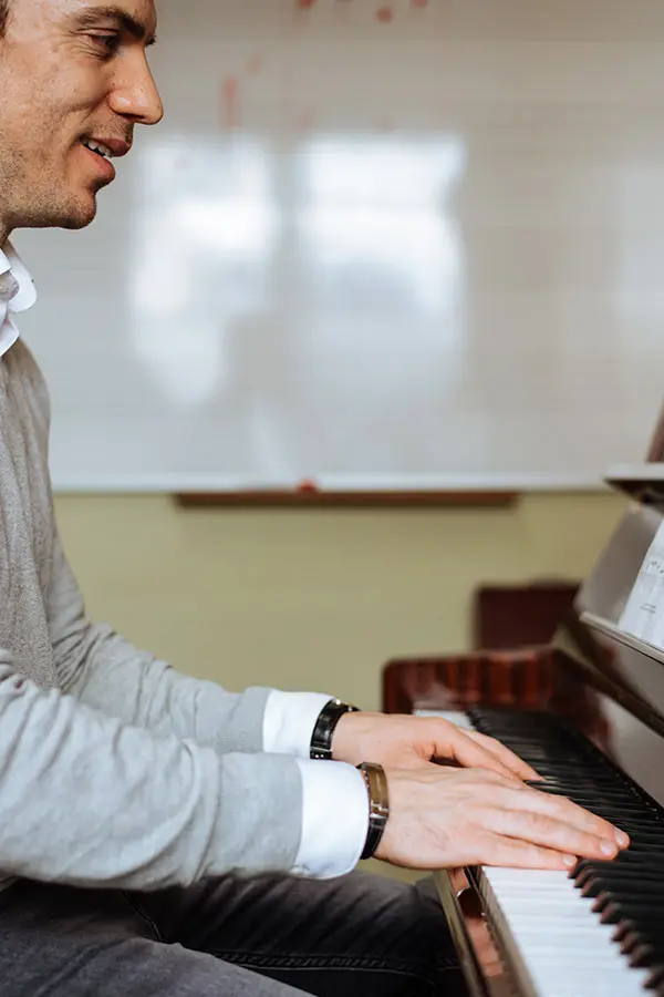 Side profile of a man playing piano near a whiteboard