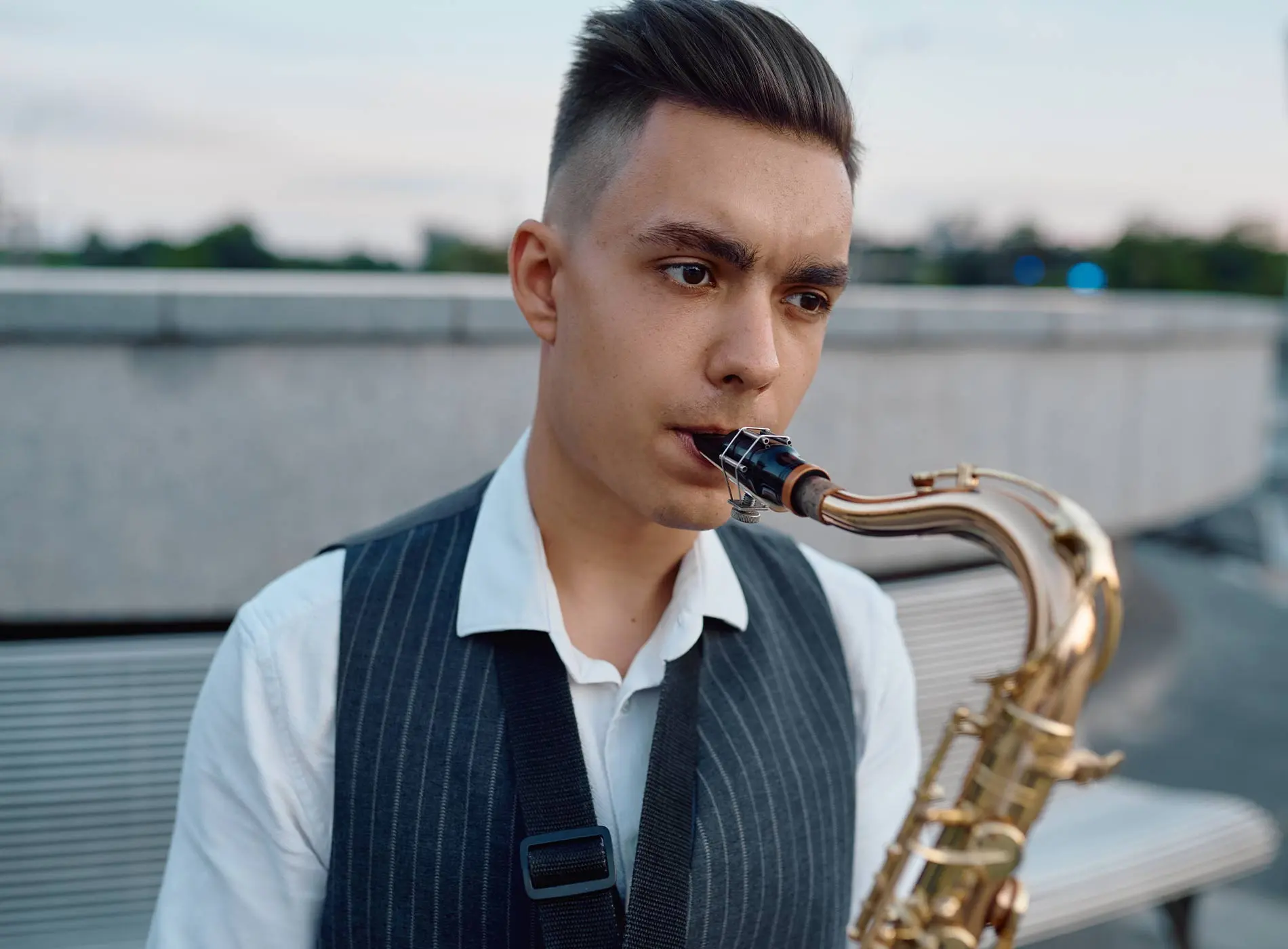 Man in vest biting saxophone to play
