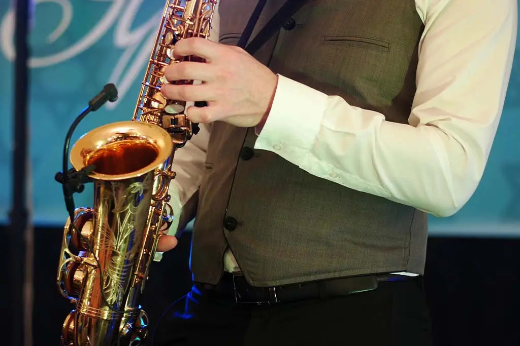 Cropped view of a man in a waistcoat playing saxophone on stage