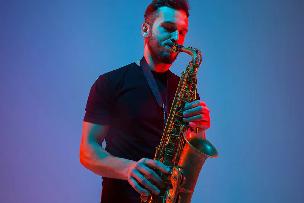 Man in a black shirt playing saxophone under red and blue light