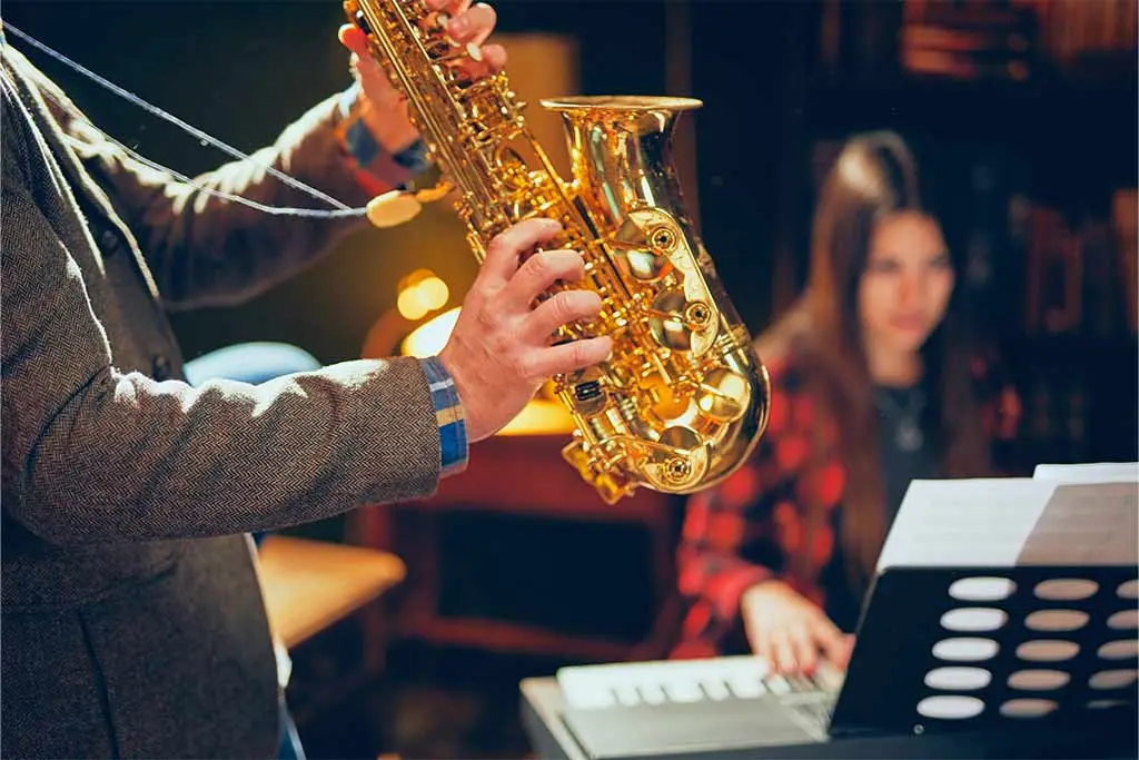Man playing saxophone with woman playing piano