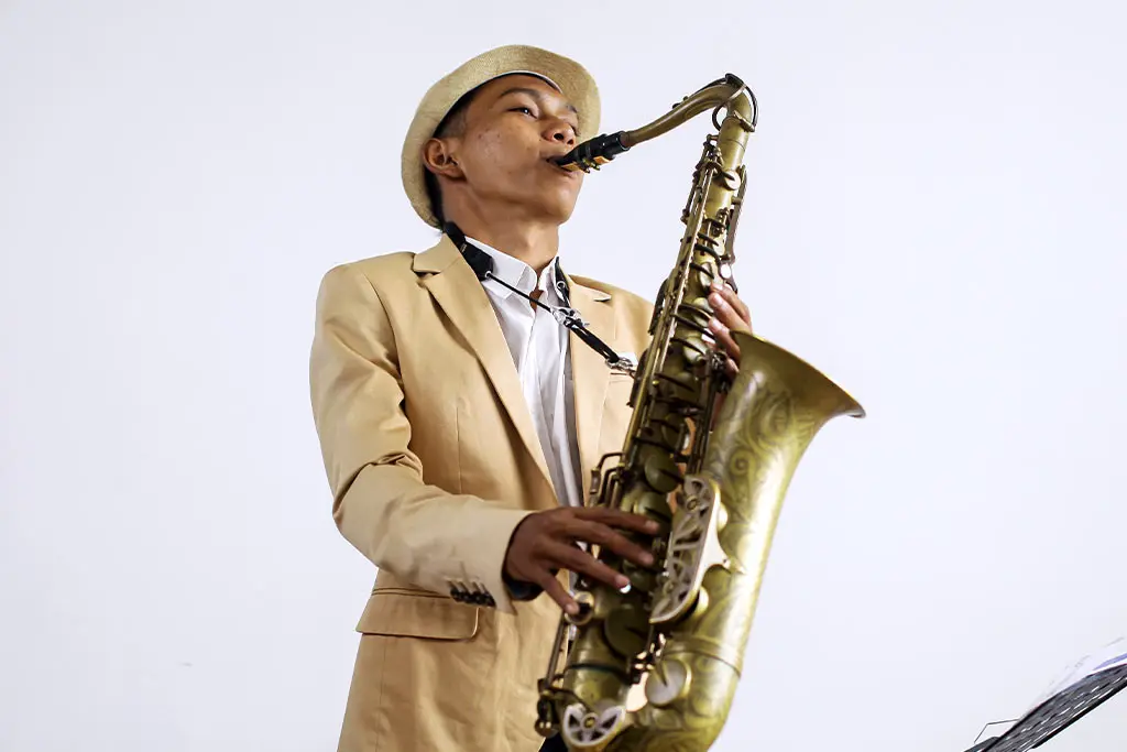 Man in a beige suit and straw hat playing tenor saxophone