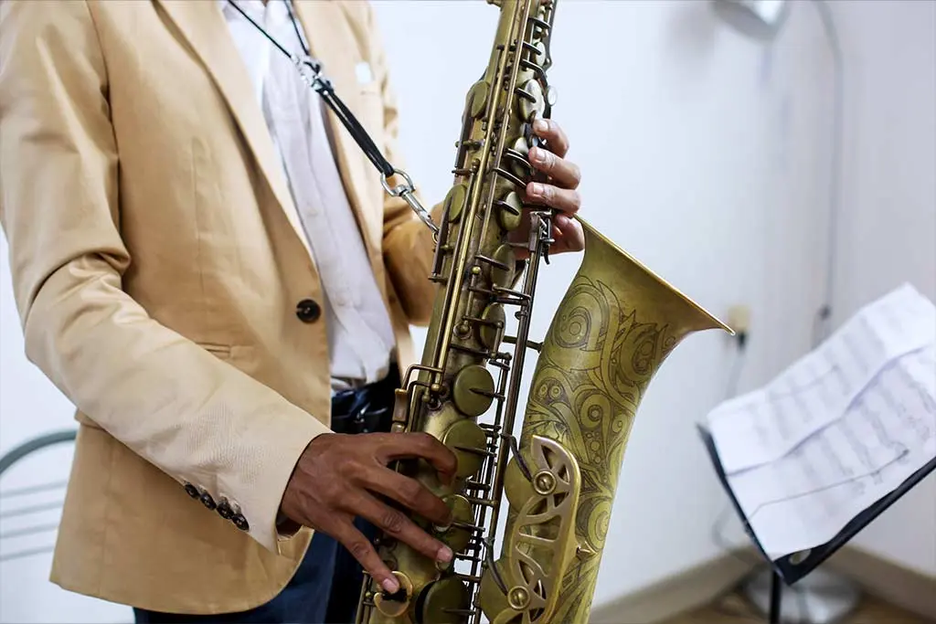 Man practising playing saxophone with sheet music