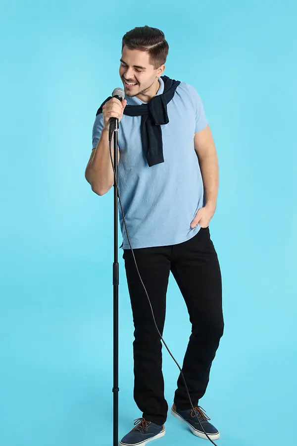 Man in a blue shirt singing into a microphone