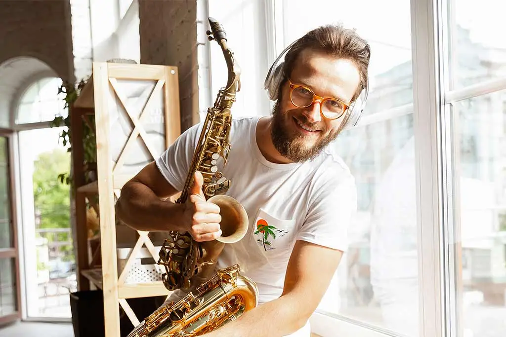 Man giving a thumbs up while holding a tenor saxophone