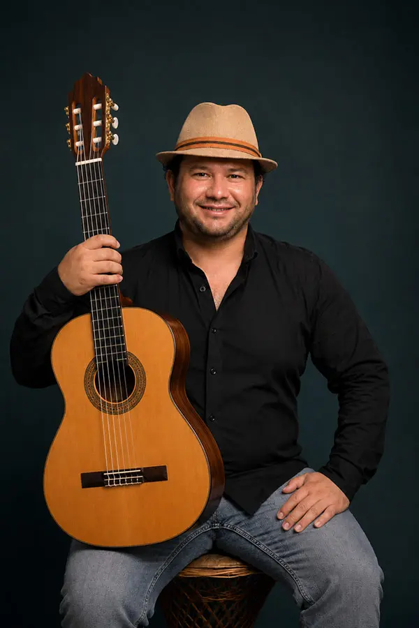 Seated man in a hat holding a classical guitar