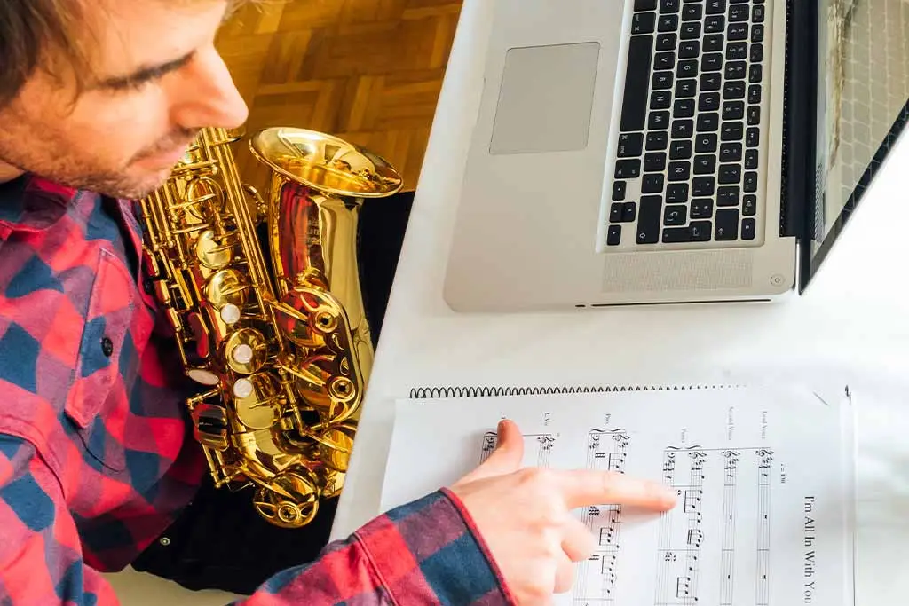 Man holding a saxophone and pointing at sheet music