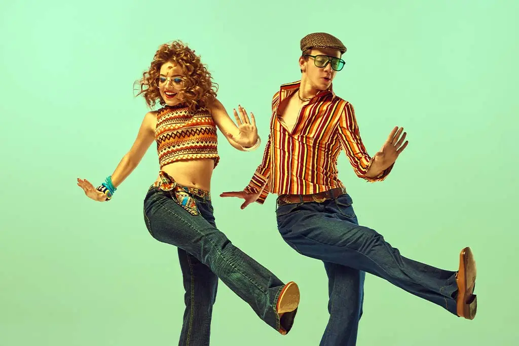 Two dancers in retro clothes kicking against a green background