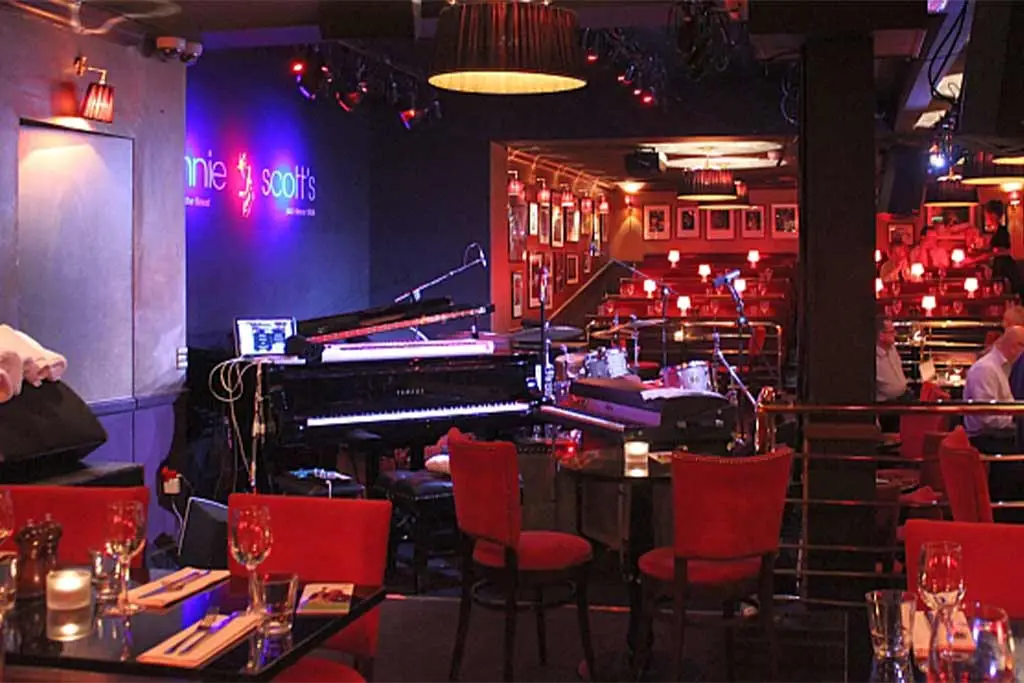 Jazz club stage with piano, drum kit and red seating