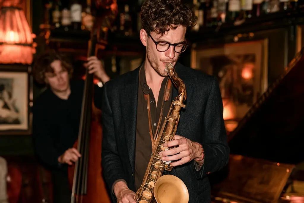 Saxophonist playing with a double bassist and drummer in a candlelit jazz bar.