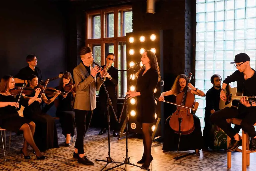 Two singers perform with violinists, a cellist and acoustic guitarist
