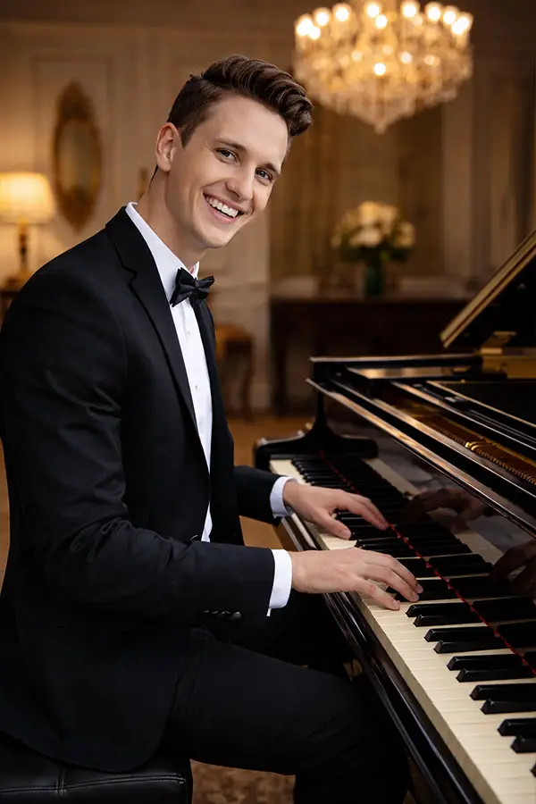Smiling man in a suit playing a grand piano