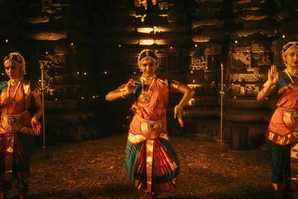 Three women performing a traditional dance in ornate costumes
