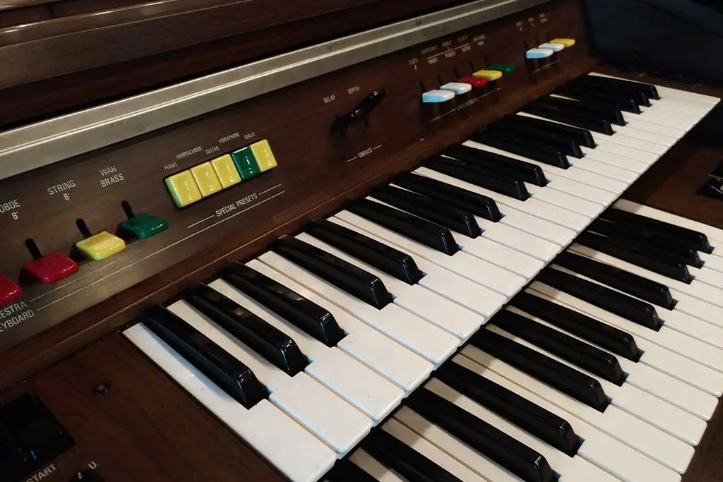 Vintage electric organ with two keyboards and coloured stops