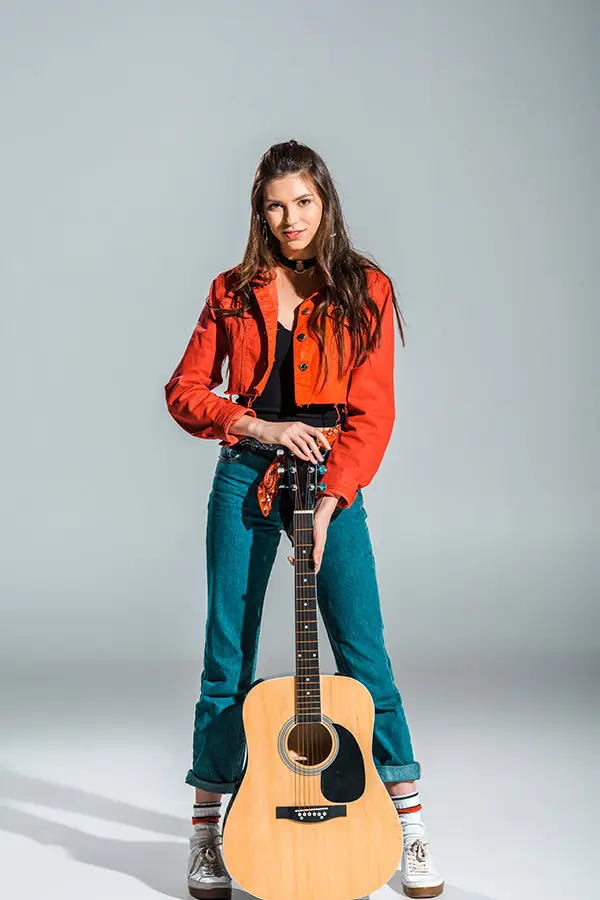 Woman in a red jacket holding an acoustic guitar