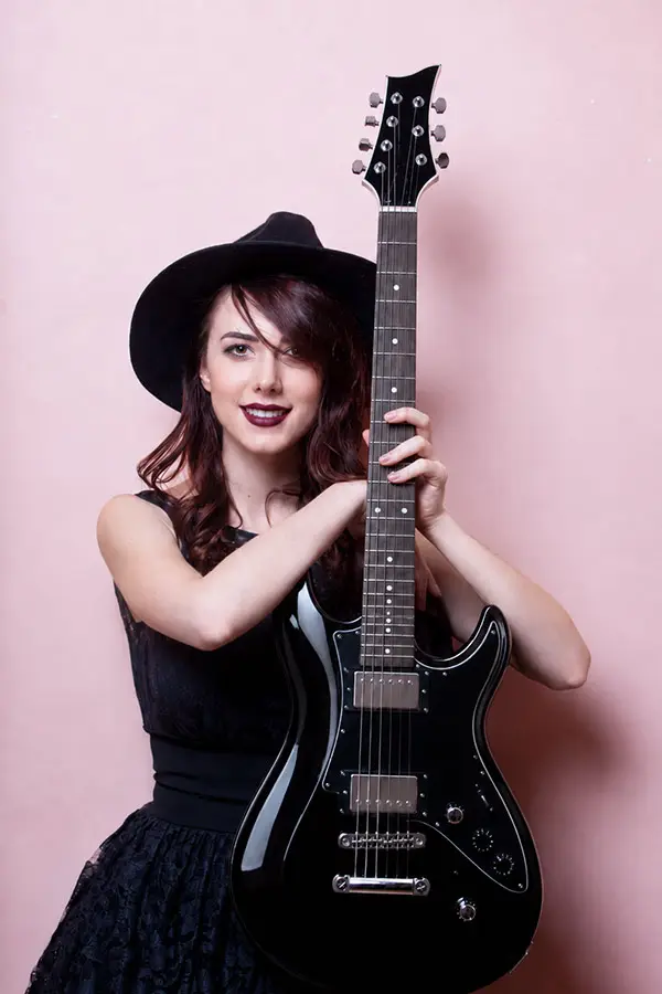 Woman in a black hat holding a black electric guitar