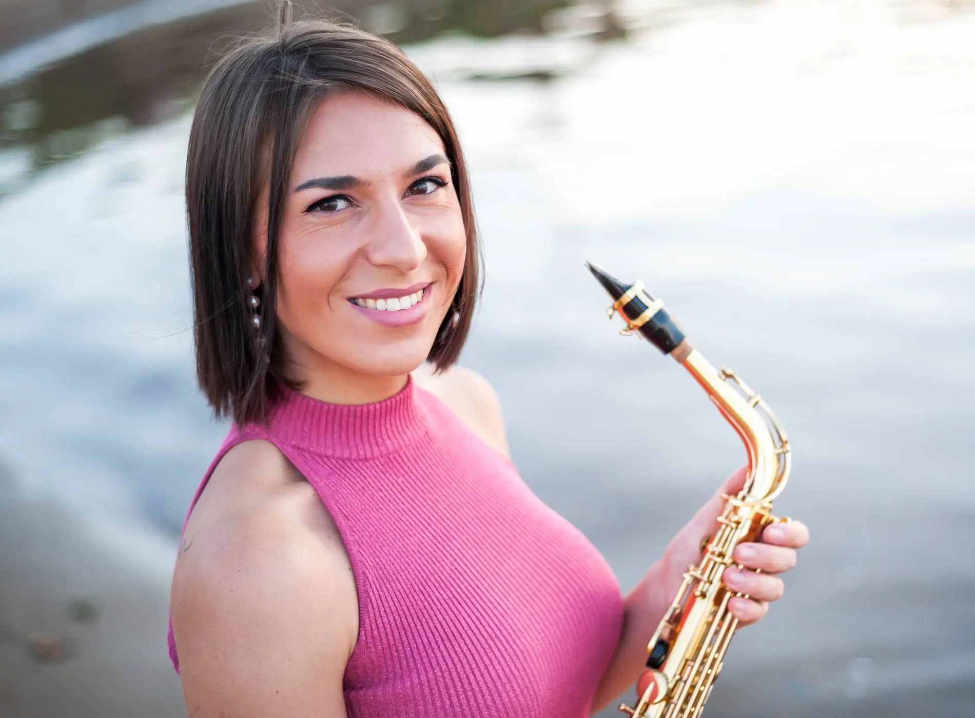 Smiling adult saxophonist holding a saxophone outdoors