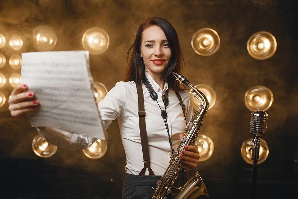 Woman holding sheet music with a saxophone on stage