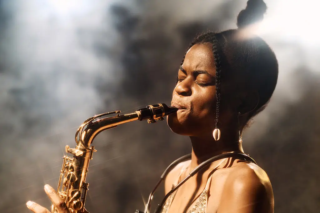 Close-up of a woman playing an alto saxophone in smoky light