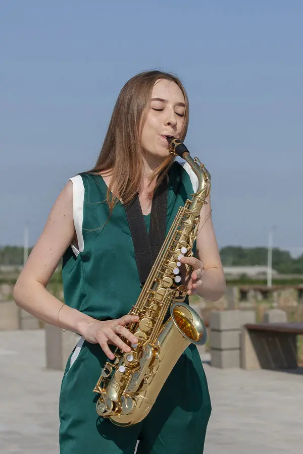 Woman playing an alto saxophone outdoors