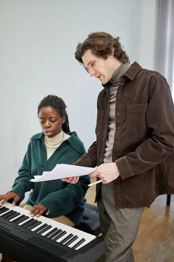 Woman playing a digital piano beside a man holding sheet music