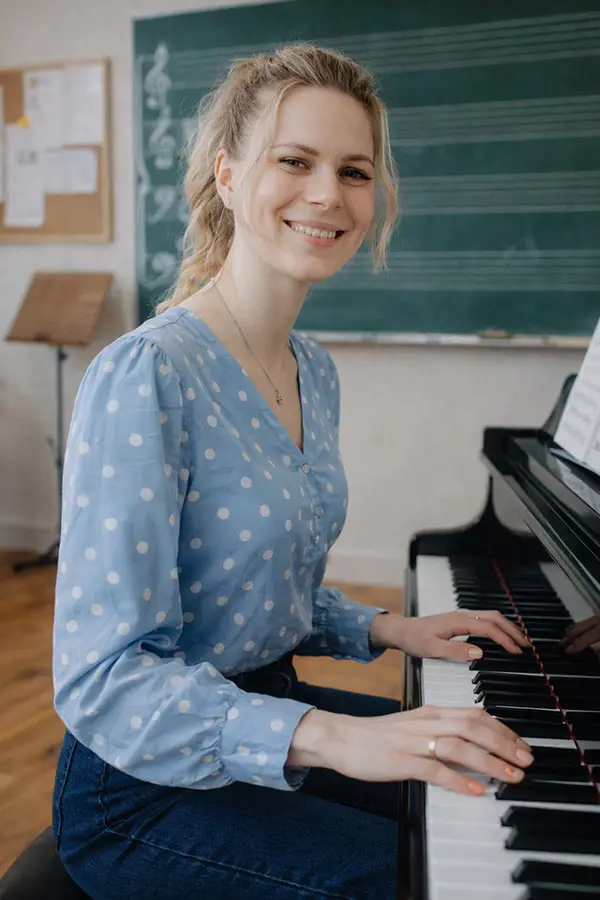 Smiling woman playing piano in a classroom