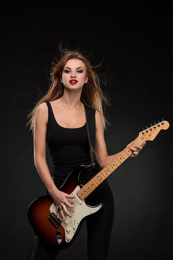 Woman in a black top playing a sunburst electric guitar